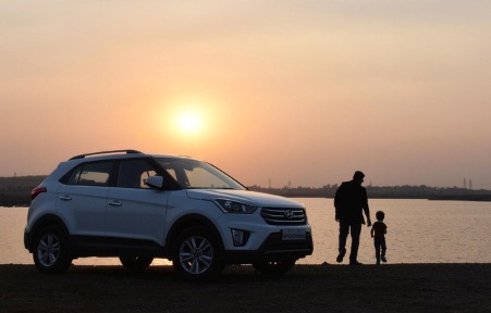 Childand falther walking toward a beach with suv in background