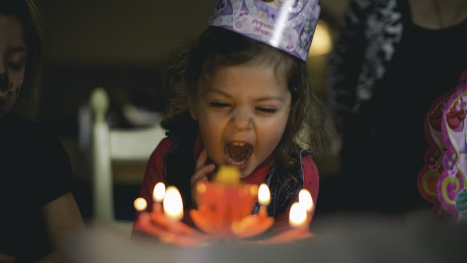 Girl trying to blow out birthday cake