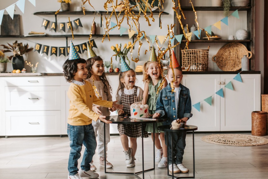 children celebrating around a birthday cake in a house